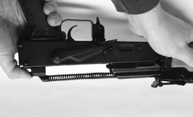 While gripping the handguard in your hand, press the back of the recoil spring cam with your thumb into the notch cut into the back of the recoil buffer. (See Illustration #11.