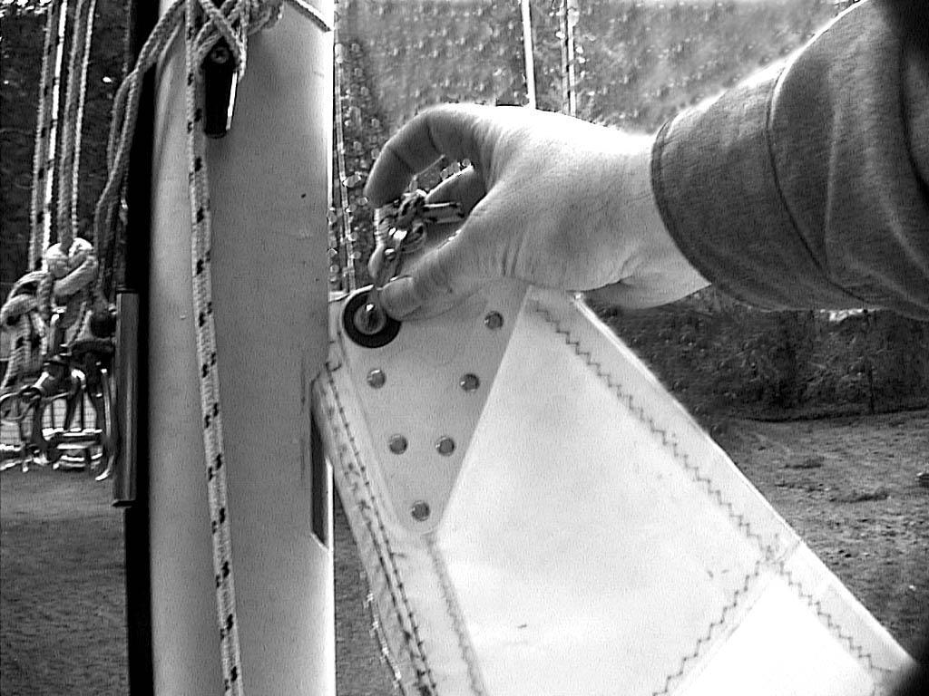 (d) Insert the top end of the boltrope (the fat rope at the front edge of the sail), or the first slug (if you have sail slugs) into the slot in the mast. Refer to Figure 3-15.
