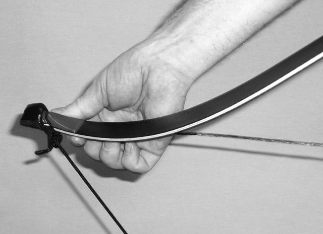 With the bow and limb tips facing up, the bow string and bow stringer cord drooping toward the floor, grip the handle of the bow and step on the stringer with
