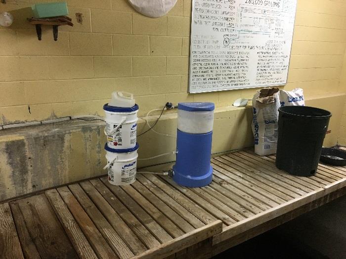 buckets of calcium hypochlorite are stored inside the pool mechanical room on a platform above the surge tank.