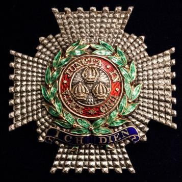 Knight Commander (KCB) The Military Star is 57-mm wide and high, in the shape of a silver cross pattée, with laurel wreaths in green around the central part of the badge and with the motto and the