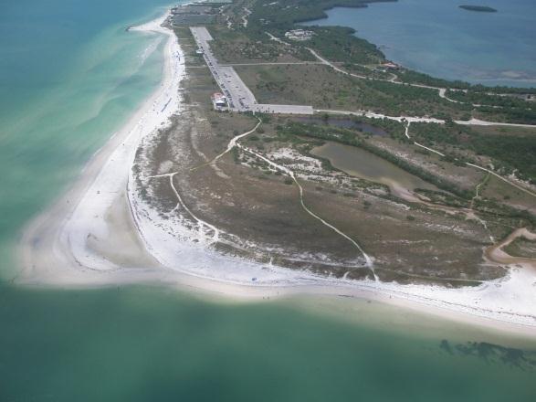The unnatural shoreline orientation and headland has resulted in a nodal point near the middle of the island, preventing a stable beach