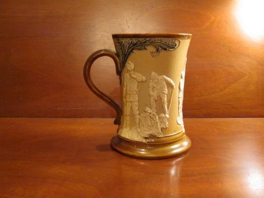 A Doulton Lambreth Golfing Pitcher circa 1900, 8 tall, decorated in green and brown, with (3) reserves depicting golfers a lost ball, putting and driving in white relief within a