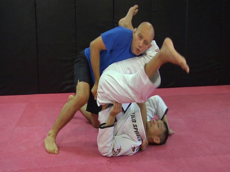 With the gi I ll use my right hand to grab his pants or belt from behind. This gives me great control. If he starts doing a backwards shoulder roll, I push down.