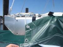The aft webbing strap is led through the clew ring of the sail and back into the buckle. The webbing should be pulled tight enough so that the bag covers the aft end of the sail.