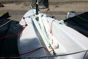 If the gennaker is not furled, hoist it, furl it and then drop it and tuck it under the jib sheets and back into the cockpit as shown.