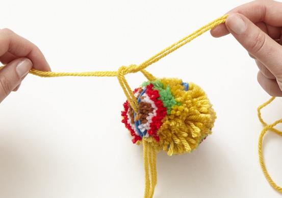 When you use a pompom maker, before removing the maker to trim the pompoms, join them by