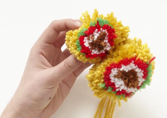 Then tie the long strand of yarn trailing from the first pompom around the center of the