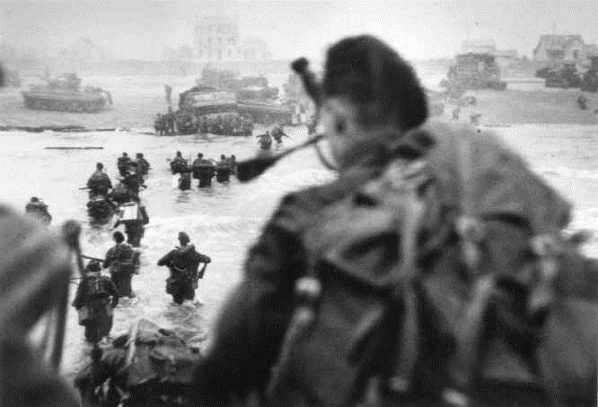 This famous photo shows the Commando Brigadier Lord Lovat and his bagpiper, Bill Millin, landing on Sword Beach during D-Day.