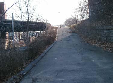 The access drive from the electrical substation up to Medford Street runs at a gradient of approximately 7%. The north side of the Medford Street bridge is supported by a sloping retaining wall.