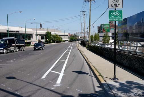 Buffered bicycle lane with wayfinding signage Green skip-striping at