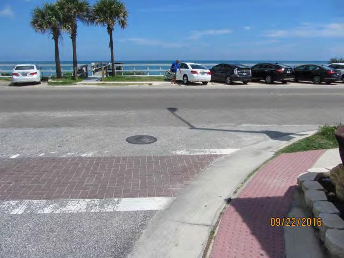 A person in a wheelchair would not be able to travel around this corner while staying on the sidewalk/pedestrian warning surface and would have to navigate themselves into the roadway or gutter.