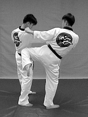 Response: Left foot step backward into forward stance, right hand circle counter-clockwise inside above head. 2 [ Left hand punch to solar plexus.