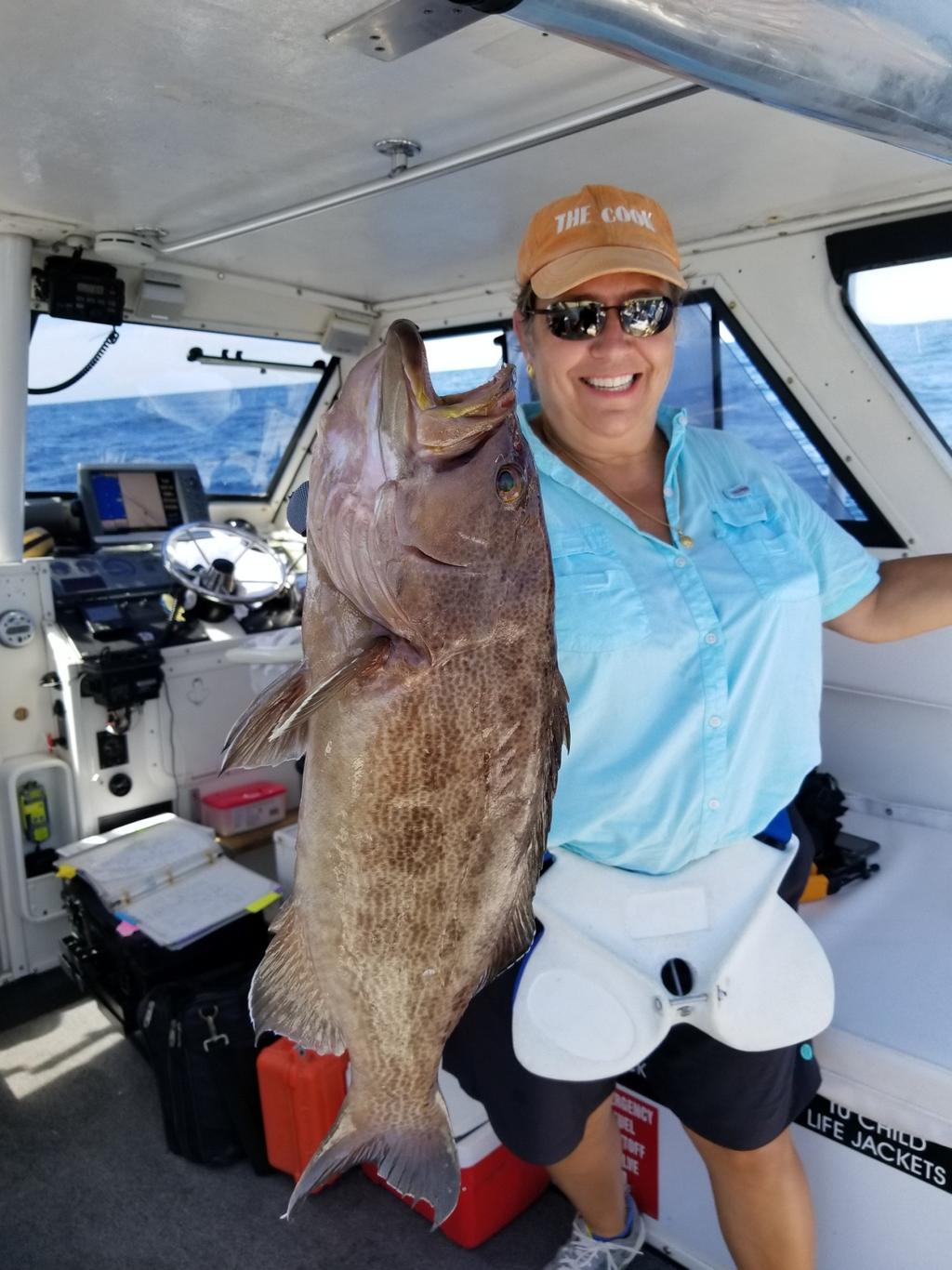 Dr. Judy Piros, Savannah, Georgia is holding up a scamp grouper, which she caught while fishing with Captain
