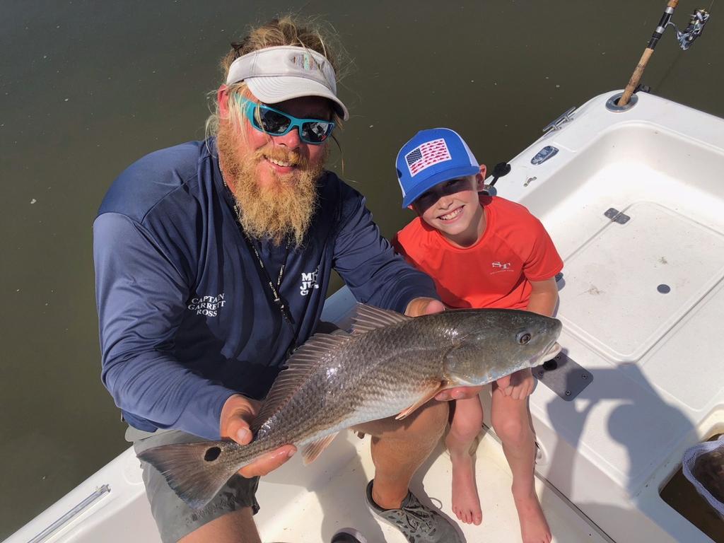 Captain Garrett Ross of Miss Judy Charters is holding Bennett Candler (10 years old) of Greenville, SC just caught red fish! Inshore fishing report!