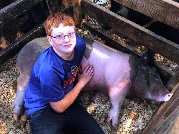 Steer and swine sell At SRF Thomas Ruth is seen with his hog. This young man is giving the profit from his sale to The Children's Table, a food pantry that helps poor people have food.