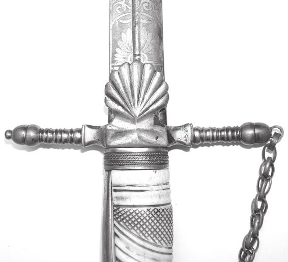 The left quillon is the same with the exception of a missing chain. The grip is profusely carved bone. There are two shell-shaped double counter guards on each side of the grip.