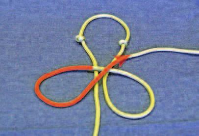 At the center point, tie a simple overhand knot. Snug the knot up. Then to the left of the knot, tie another simple overhand knot.