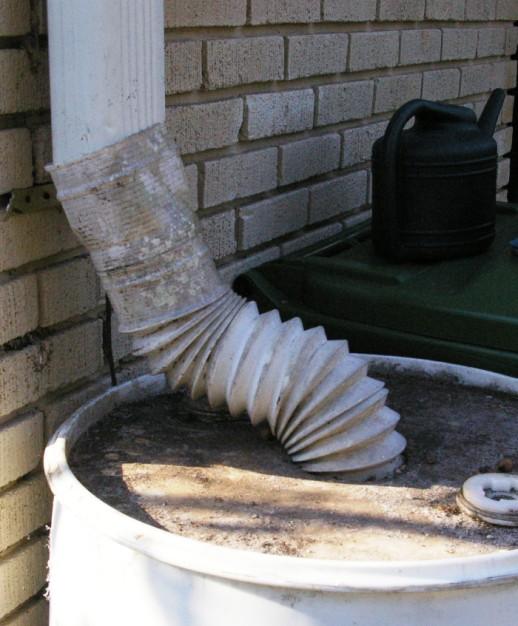 2. Elevate the barrel on the cinder blocks. Using the metal cutters, cut the gutter downspout 1-2 ft. above the top of the barrel.