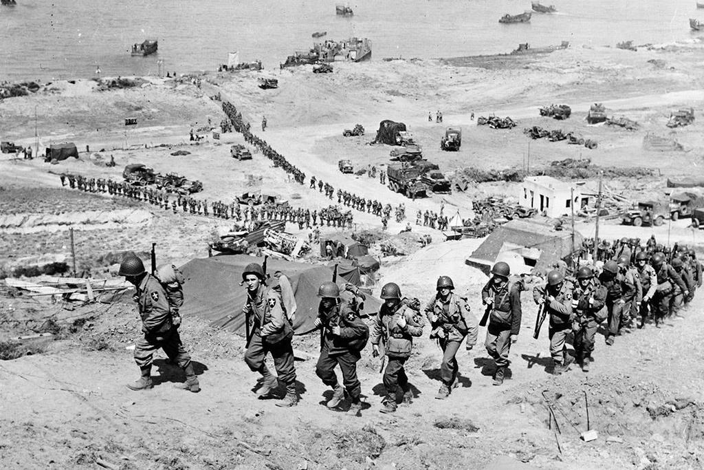 June 18, 1944: US Army reinforcements march up a hill past a German