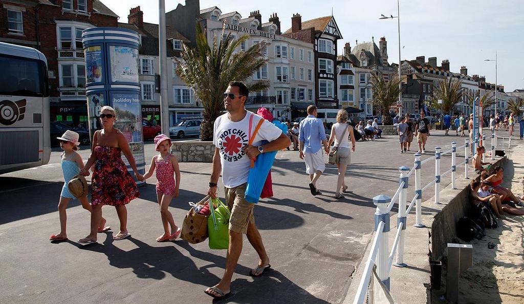 Tourists walk along the beach-front in the Dorset holiday town of