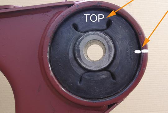 Make sure that the orientation index marked TOP (in white color for illustration purposes) faces upward and that the bushing position locator of the replacement bushing is aligned with the bushing