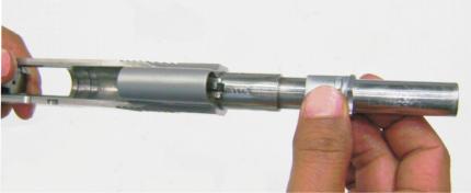 Move slide rearward, approximately ½ inch grasp firmly to hold in place, and depress recoil spring plug with thumb. 4.