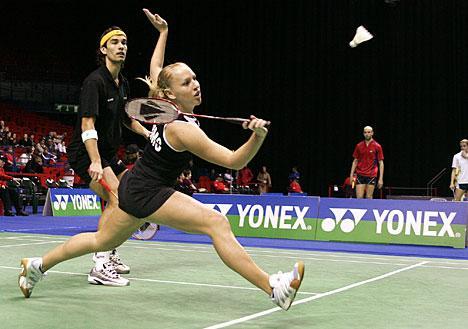 BADMINTON Badminton is a racket sport played by either two opposing players (singles) or two opposing pairs (doubles). The badminton court is rectangular and is divided by a net.