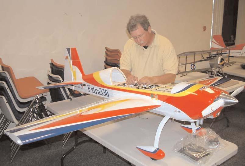 Gary demonstrated a paper plate glider he plans to distribute to the Cub Scouts for their entertainment CAROLYN SCHLUETER PHOTO (LEFT) (RIGHT) Gary Pyles assembles his 30%-scale AK Models Extra 330L,