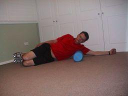 D. Latissimus/Lateral Trunk Foam Roller Release The golfer lays on their side with their arm above their head, foam roller resting against the under side of the shoulder.