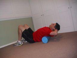 Foam Roller Upper Back Release The golfer lays on their back supporting their neck with their hands and a foam roller under their upper back.