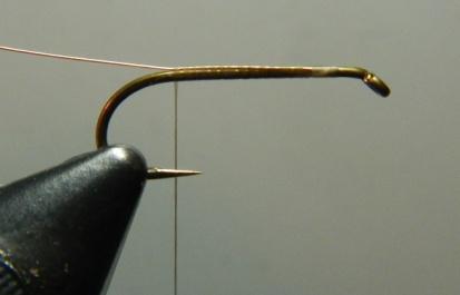) Using edge-to-edge wraps, bind the ribbing material down on top of the shank as you wrap the thread to the rear of the hook.