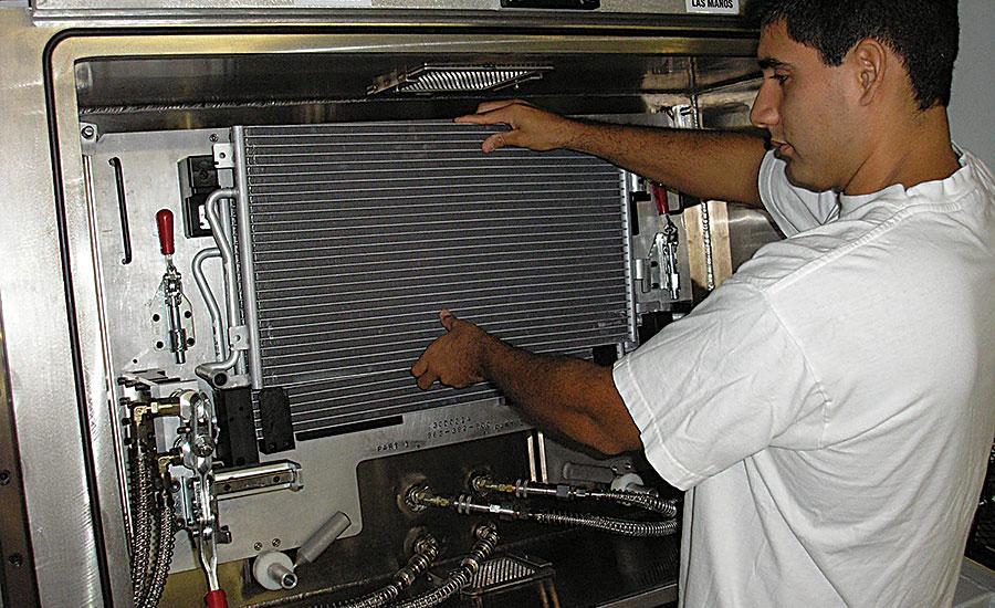 An operator loads an air-conditioner condenser into a hard-vacuum test chamber.