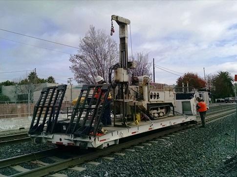 This lo-railer had a hole cut into it so the drill rig could drill under the tracks while stationed on the track at pre-determined locations.