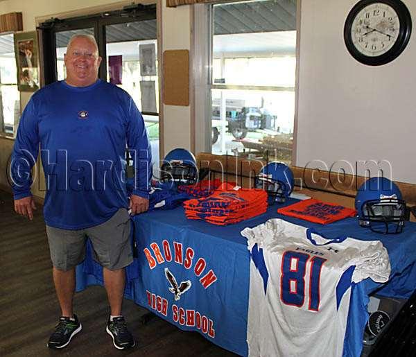 Bronson High School Head Varsity Football Coach Seth Stebbins stands with some BHS Eagles gear.
