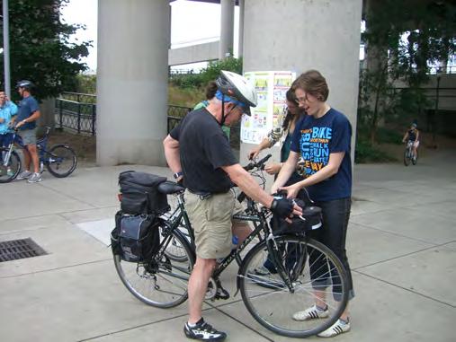 80 A volunteer transportation ambassador installs a free bike bell during a Share the Path event.