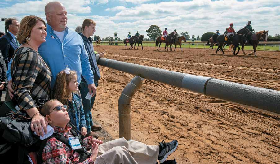 Cody Dorman of Richmond enjoys a close-up view of horses on their way to the post with his parents Leslie, left, and Kelly and sister