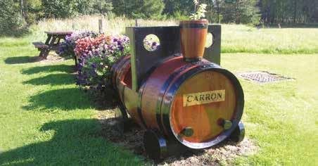 42 Whisky casks housing floral display, Carron Beyond Carron, the river makes intermittent appearances on your left as the track winds past places with lovely Gaelic names such as Dalmunach,