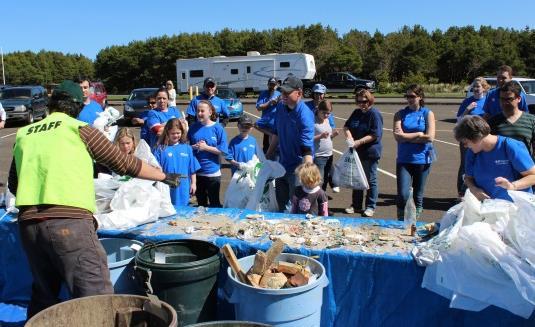 Vlunteers are asked t separate plastic bttles frm the rest f the debris, and helpers frm OBRC are n hand t help separate and clean the bttles. The middle pht is frm the Nehalem Bay Cleanup.