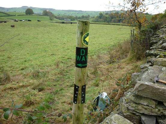 left, way marked. The footpath crosses the stonewall halfway down the field, now way marked.