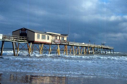 3. The wooden Sunglow Fishing Pier in Daytona Beach Shores had its seaward end destroyed (Photo 8). Photo 8. Sunglow Fishing Pier lost its seaward end during Thanksgiving Storm, 1984 4.