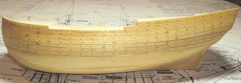 With an ample supply of pre-formed planking strips, you can start gluing them onto the hull. Instead of cutting them into smaller lengths, you can glue one continuous strip from bow to stern.