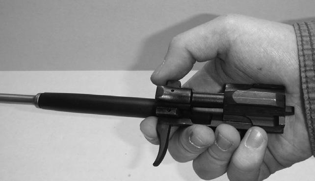 To remove the bolt from the bolt carrier, hold the bolt carrier in your primary hand so that the cocking handle faces to the left. (See Illustration #14.