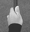 The thumb is placed slightly on the right side of the shaft with the gap between the thumb and index finger closed.