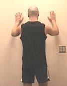 As you are able to stretch the hand and arm higher, you should move your body closer to the wall.