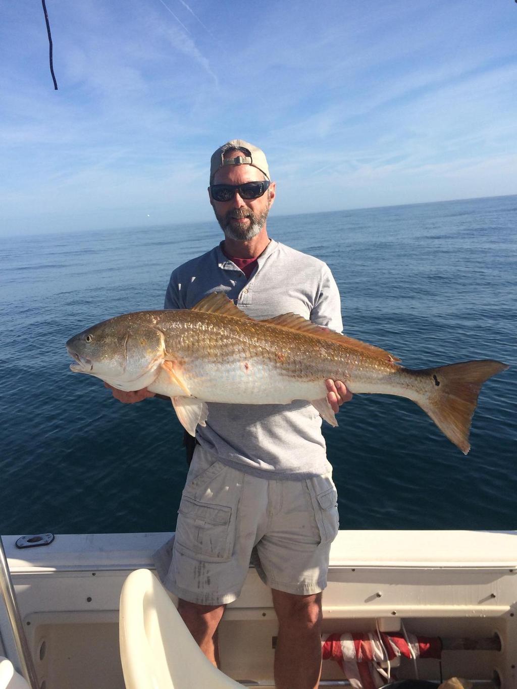 Daryl Chandler is holding a nice trophy red fish that he caught while jigging with paddle/screw tails at Gray s Reef Sanctuary.