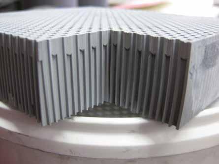 The carrier material is extruded to monolithic honeycombs and the channels are alternatingly closed with plugs similar to diesel particulate filters in the automotive business.