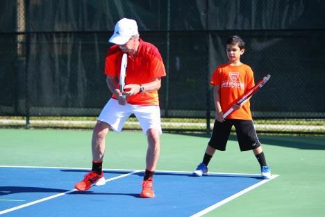 Players are in an athletic position with feet shoulder width apart and knees bent and their racquet in the middle of