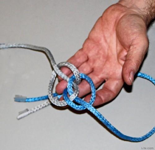 There are two large openings in the working part of this knot. Take one end and tuck it up through the opposite one of these large openings.