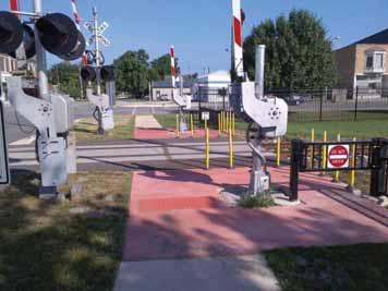 A better option is to extend the sidewalks through the rail crossing,